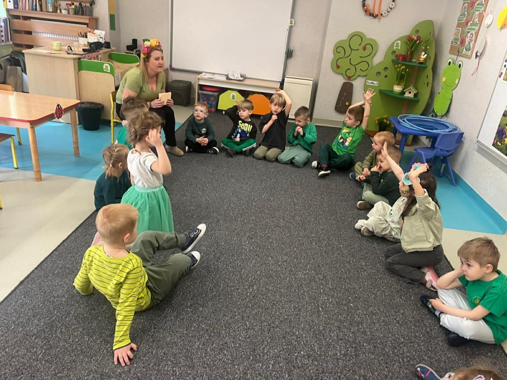 Dzieci słuchają zagadek czytanych przez nauczyciela