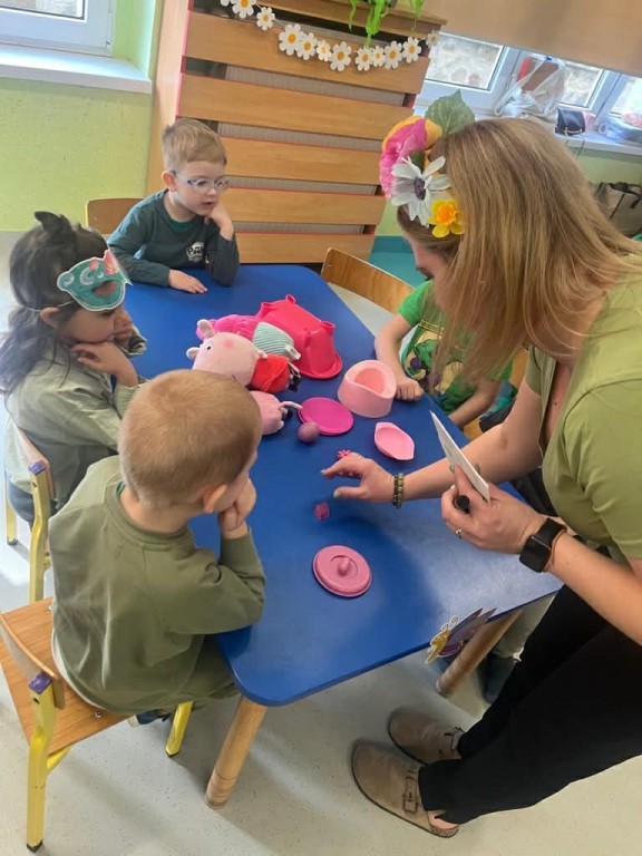 nauczyciel liczy zebrane przez dzieci przedmioty różowe