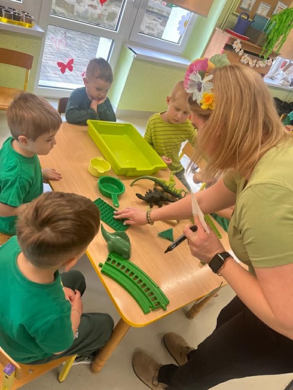 nauczyciel liczy zebrane przez dzieci przedmioty zielone