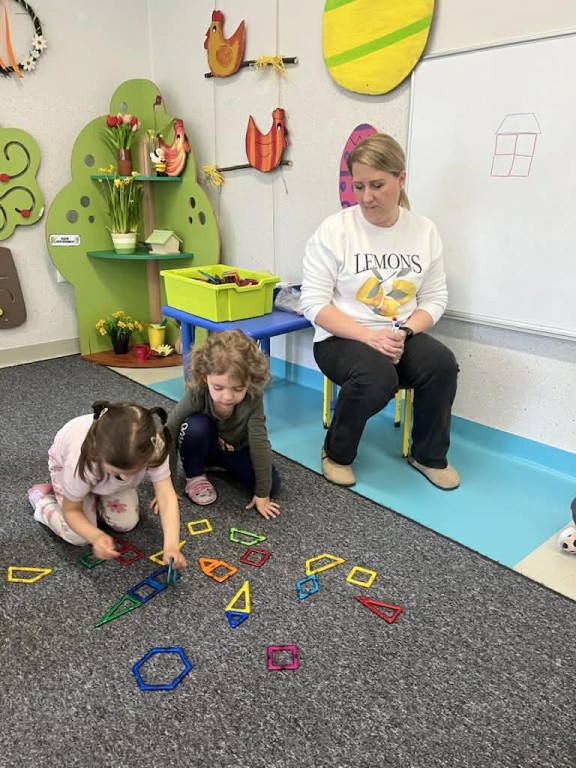 Dzieci układają z klocków wzór narysowany na tablicy przez nauczycielkę