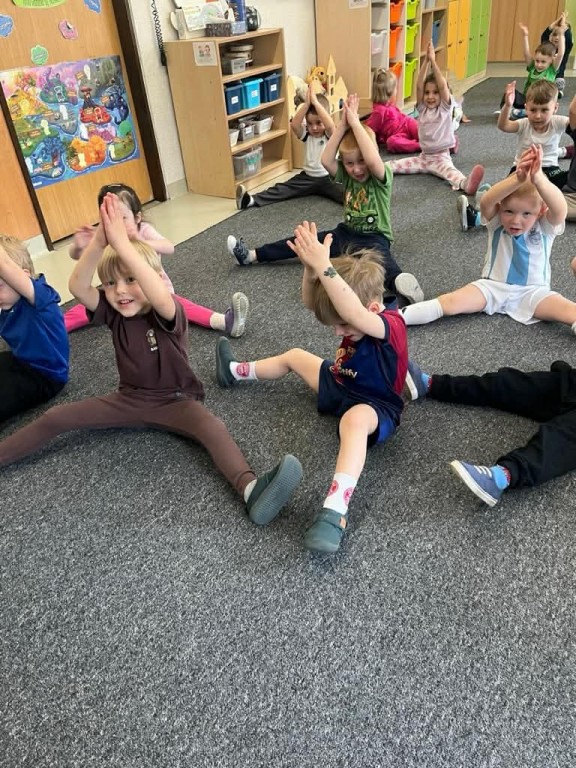 dzieci wykonują ćwiczenia w postawie siedzącej