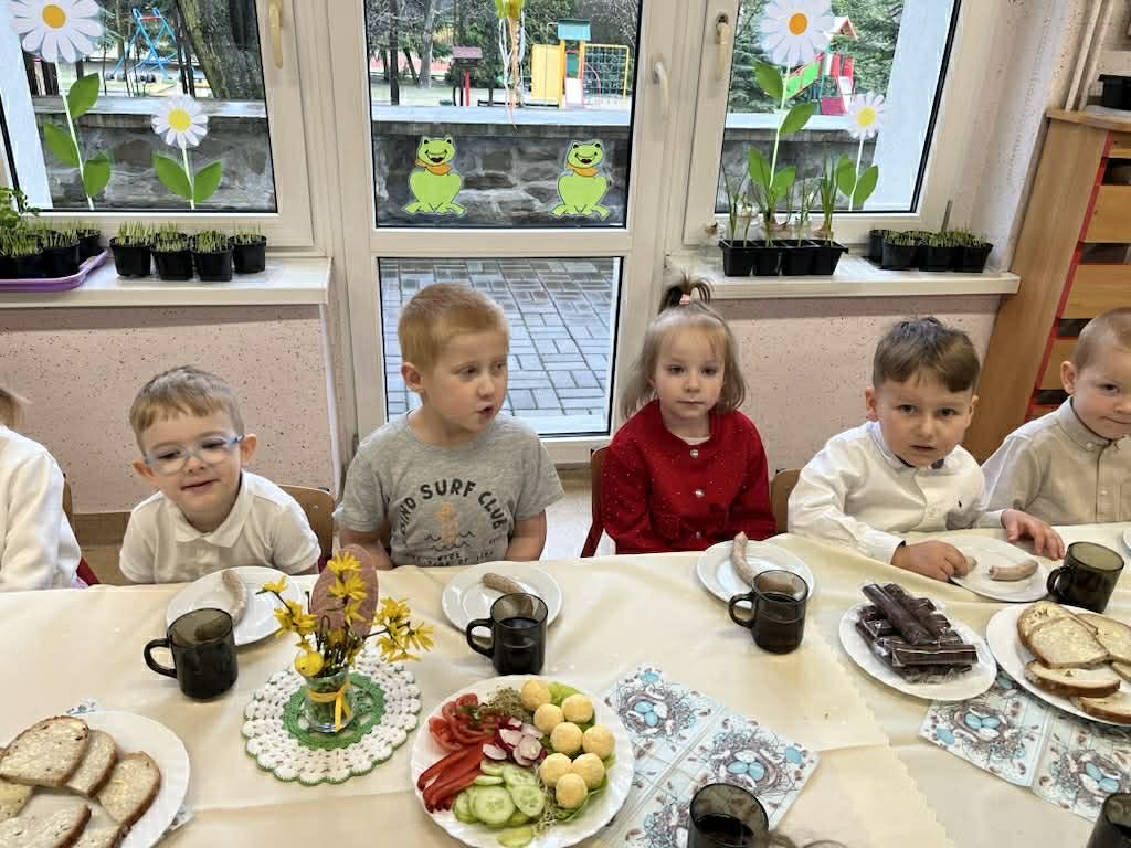 Dzieci siedzą przy zastawionym stole