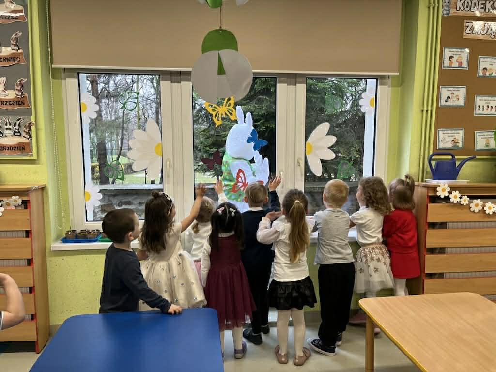 Dzieci wyglądają przez okno machają Zającowi
