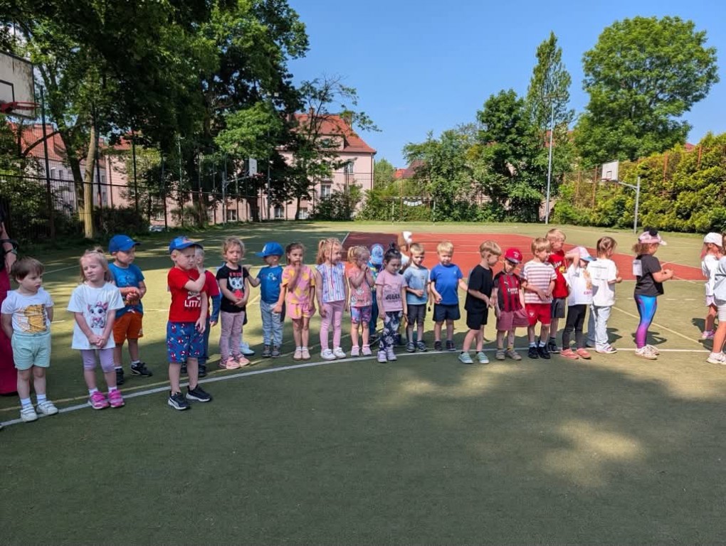 Dzieci w sportowych strojach stoją na linii startu